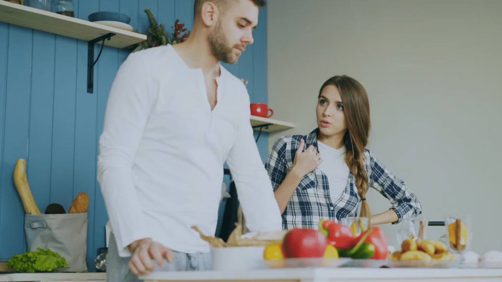 Couple standing in a kitchen during a disagreement, showing common communication patterns in relationships