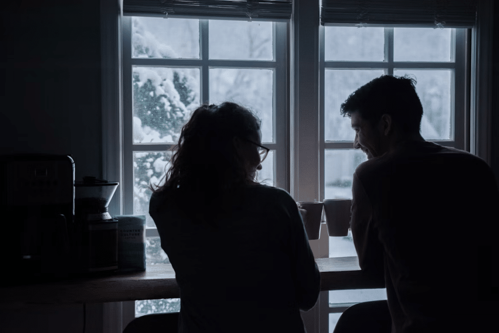 Couple sitting together by a window having a calm, supportive conversation that reflects healthy communication